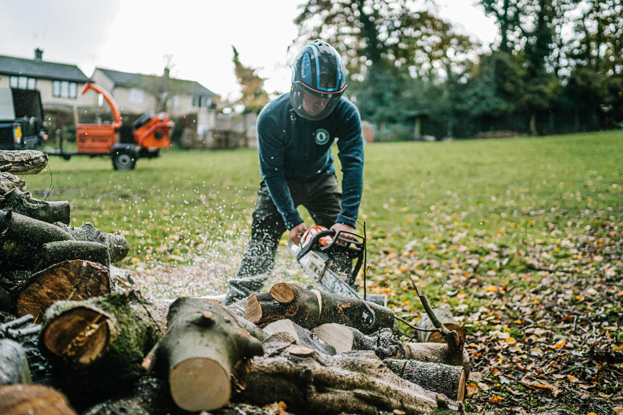 An Arborist from the Silver Oak team using a chainsaw cutting logs